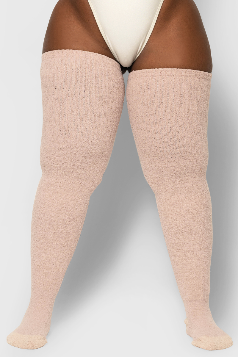 A pair of thigh-high socks in a light pink color, made of brushed acrylic fabric, showing the cuff and the texture of the fabric.