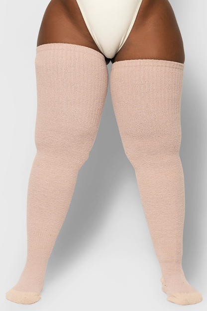 A pair of thigh-high socks in a light pink color, made of brushed acrylic fabric, showing the cuff and the texture of the fabric.